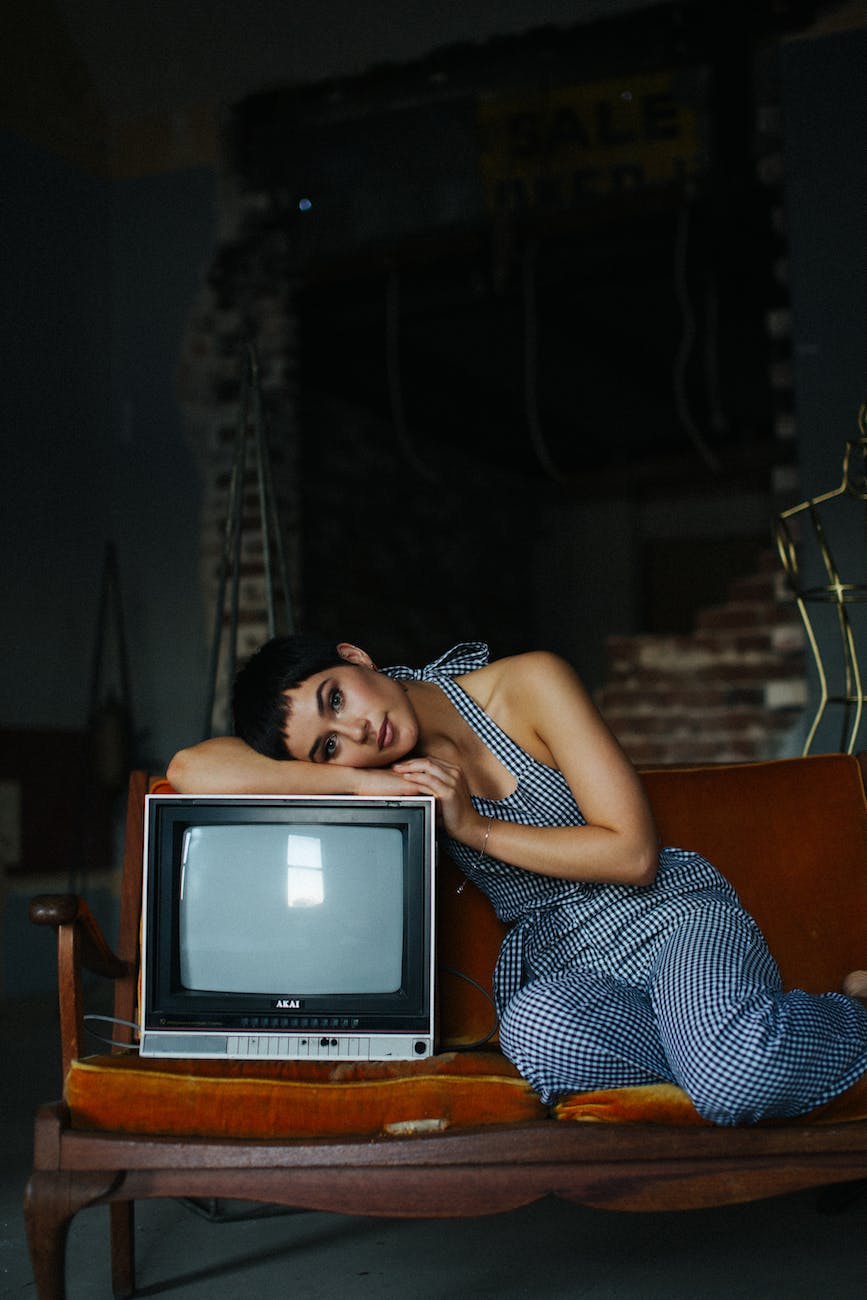 shorthaired woman leaning on retro tv set in studio